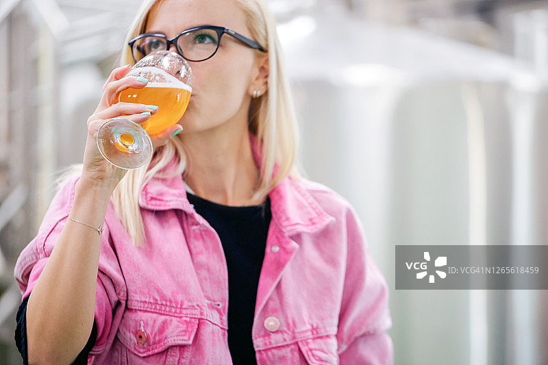 女人在啤酒厂品尝精酿啤酒从一个杯子检查质量图片素材