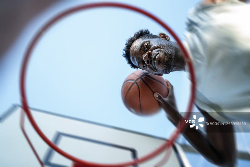 黑人男篮球运动员在灌篮。篮球框的底部视图图片素材