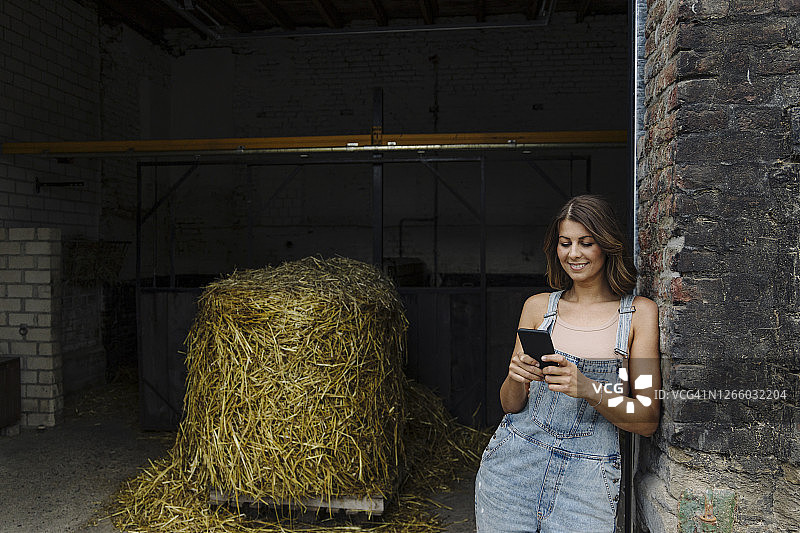 一名年轻女子在农场的谷仓里使用手机图片素材