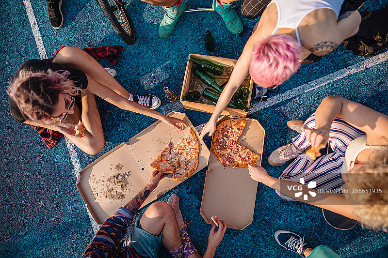 一群朋友在体育场上享用披萨和啤酒图片素材