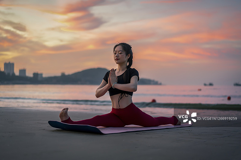 一个年轻女人在海滩上做瑜伽图片素材