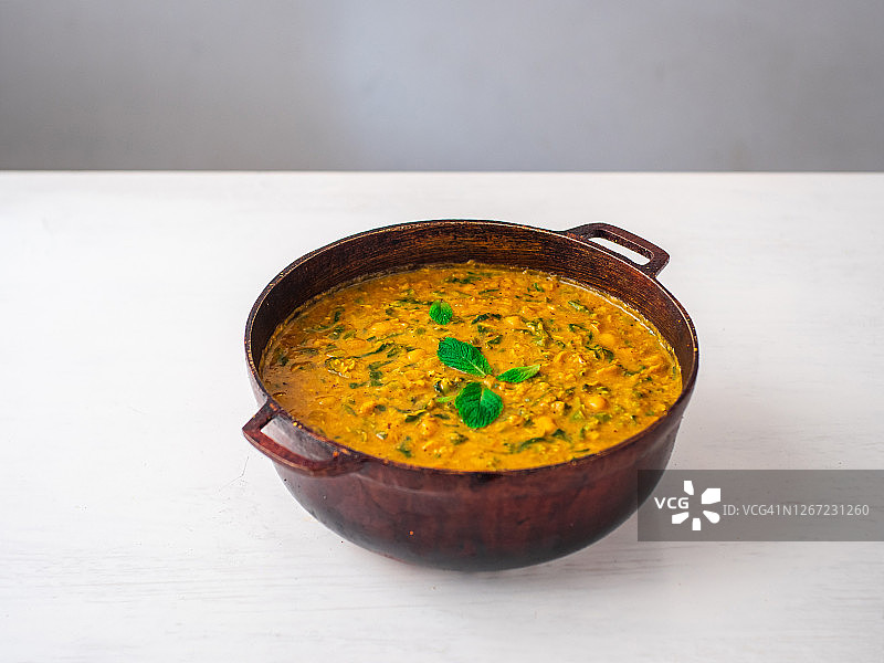 印度素食:白色背景上的鹰嘴豆和菠菜咖喱锅图片素材