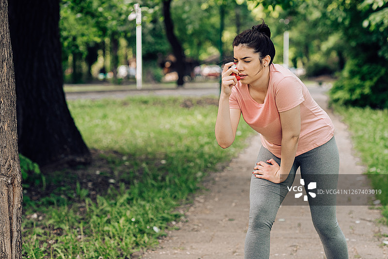 女孩在公园慢跑时使用哮喘吸入器图片素材