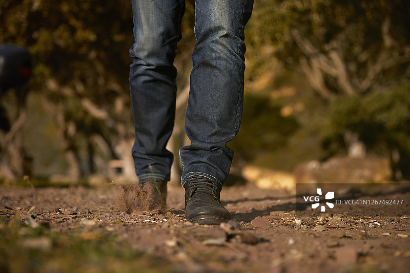 穿着牛仔裤和靴子的男人走在土路上图片素材