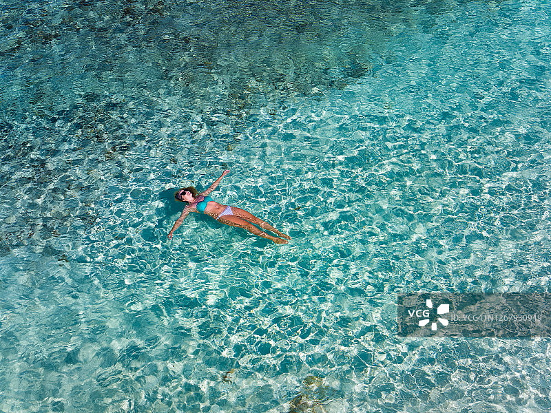 迷人的女人漂浮在水晶清澈的水在加勒比热带海滩图片素材