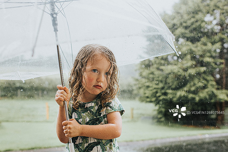 失望的小女孩在暴雨中撑着伞图片素材