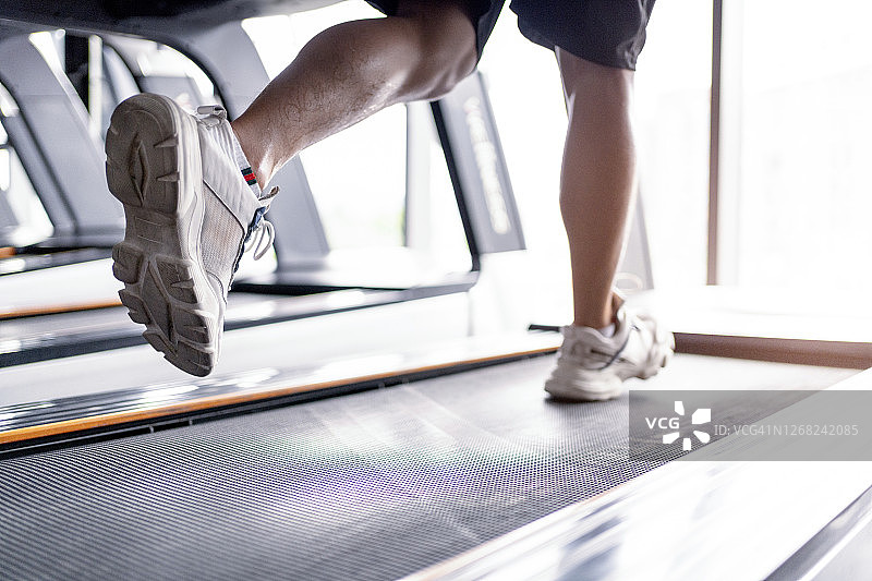 特写镜头的一个不认识的运动员在跑步机上在一个健身房图片素材