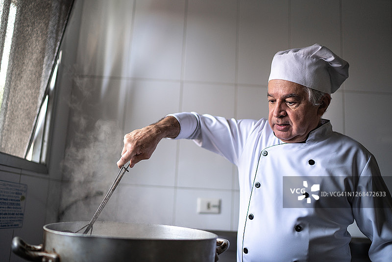 高级厨师在一个工业厨房里准备油炸食品图片素材