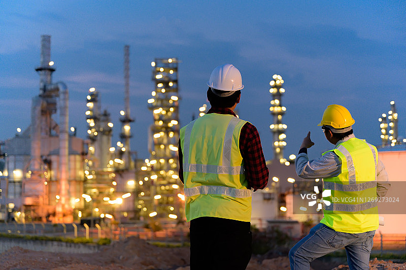 两名工程师在工业园区的石油炼油厂上夜班图片素材