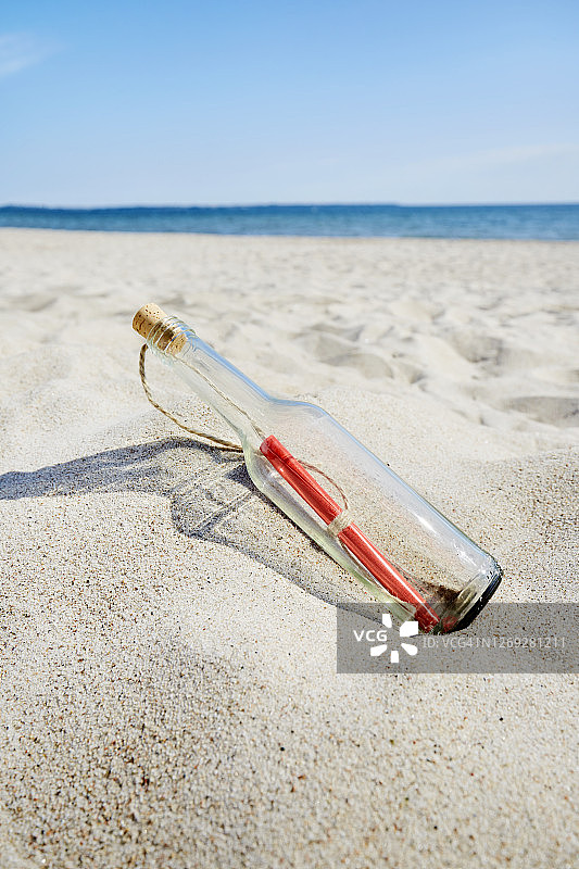 夏日蓝天下的海滩上，瓶中的信息图片素材