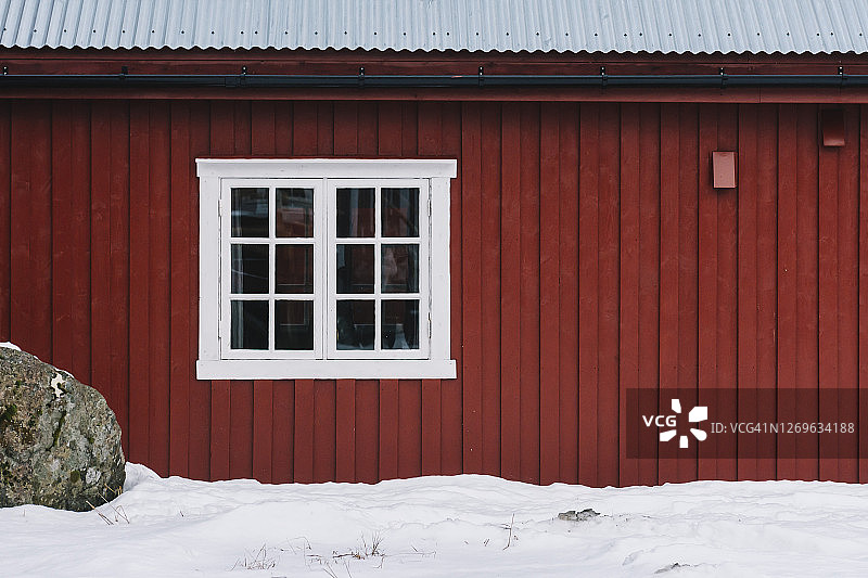 挪威罗浮敦群岛，白雪环绕，白色窗框的红色渔人小屋图片素材