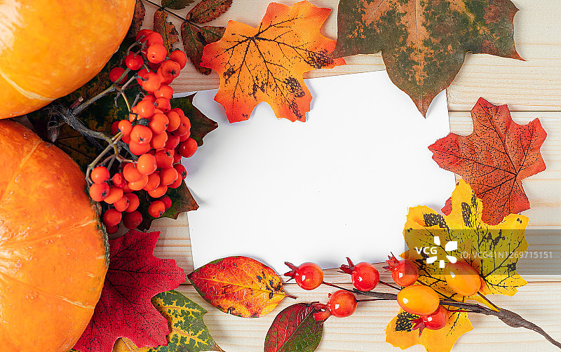 橙色南瓜，枫叶，浆果和模拟纸空白木质背景。你好秋贺卡，秋时光概念。平的。本空间图片素材