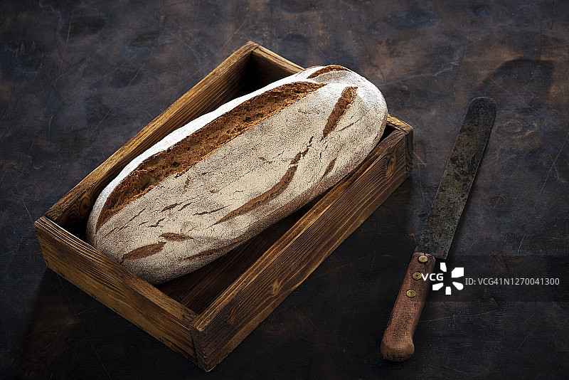全麦黑麦面包，放在木盒托盘上，放在深色的木头上图片素材
