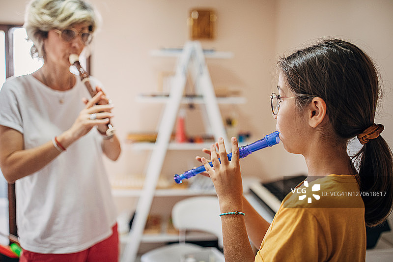 一个学龄前女孩在儿童发展中心和她的音乐老师一起学习吹笛子图片素材
