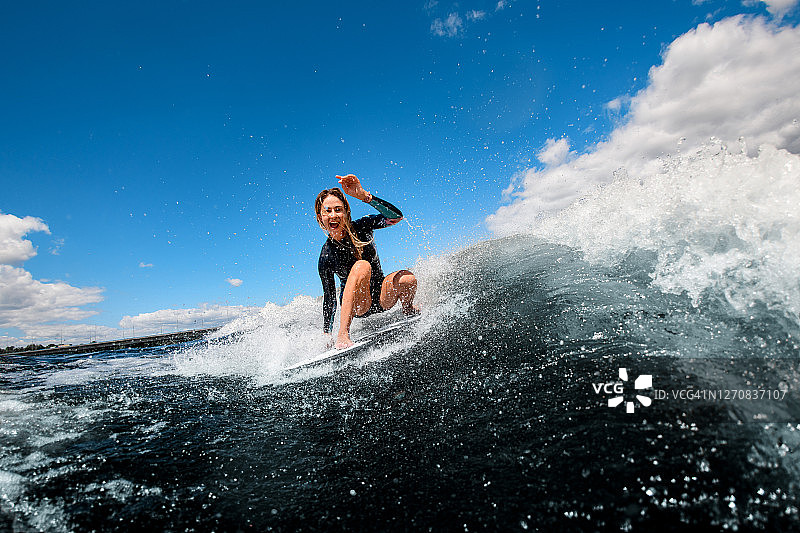 美丽的景色，欢快的女人坐在冲浪板和骑在波浪图片素材