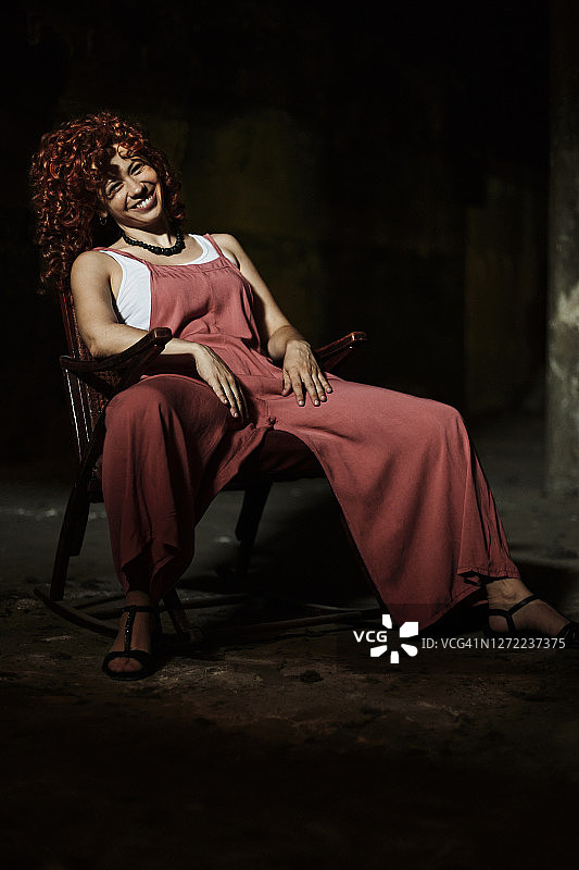 坐在暗室椅子上微笑的红发女人图片素材