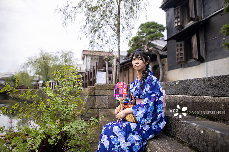 十几岁的女孩坐在一个古老的日本村庄的台阶上图片素材