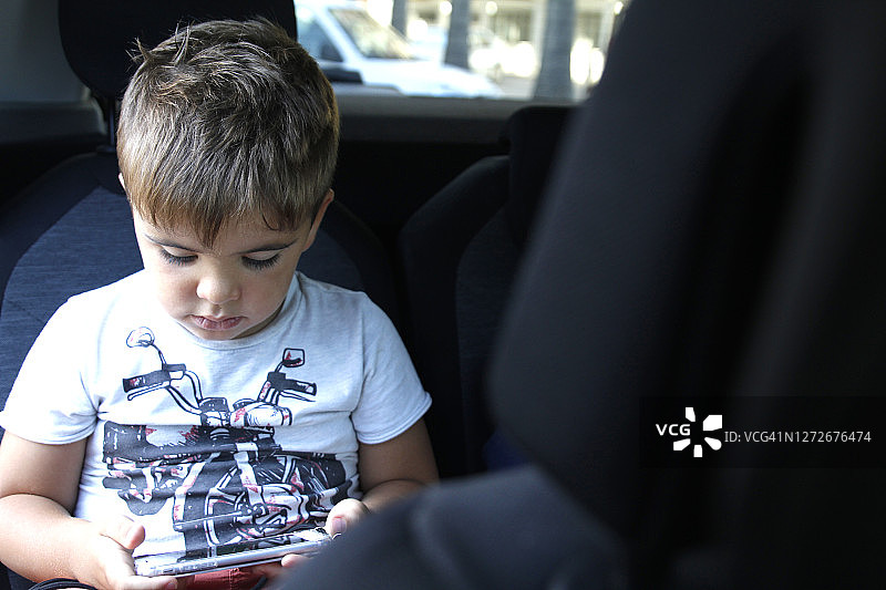 小男孩在座椅车上玩电子游戏图片素材