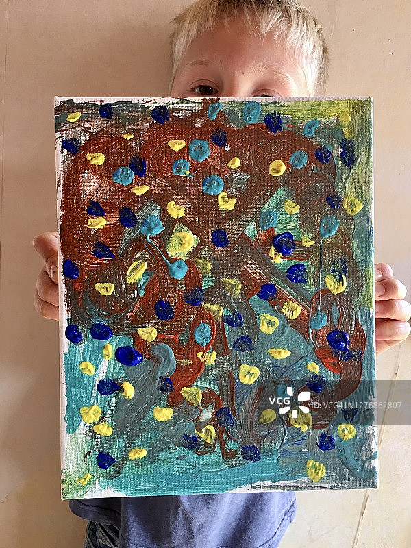 孩子拿着他的抽象丙烯画在画布上图片素材