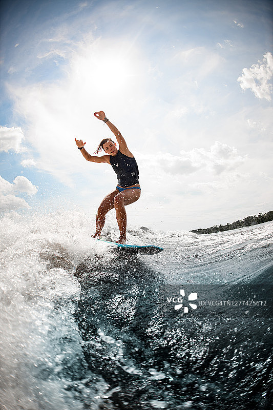 女子平衡在尾流板上的高浪对着蓝天图片素材