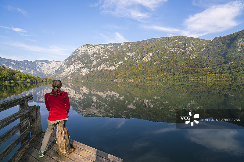 在斯洛文尼亚的朱利安阿尔卑斯，博欣湖的早晨与一位女士享受云雾在湖水中的倒影图片素材