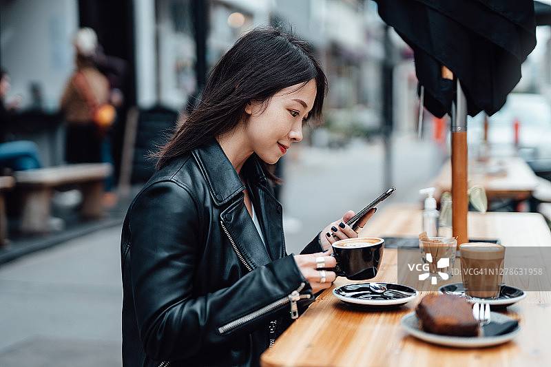 年轻女子在咖啡馆喝咖啡时用手机图片素材