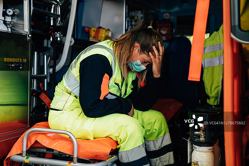 年轻的护理人员是悲伤的女人，坐在救护车上图片素材