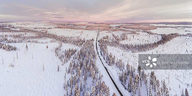 日落时分，芬兰拉普兰的北极圈，冰雪覆盖了冬季的道路图片素材