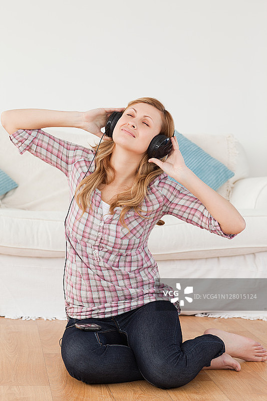 快乐的女人坐在地板上听音乐图片素材