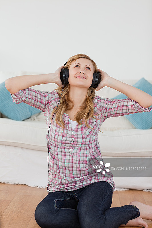 快乐的金发女人戴着耳机听音乐图片素材