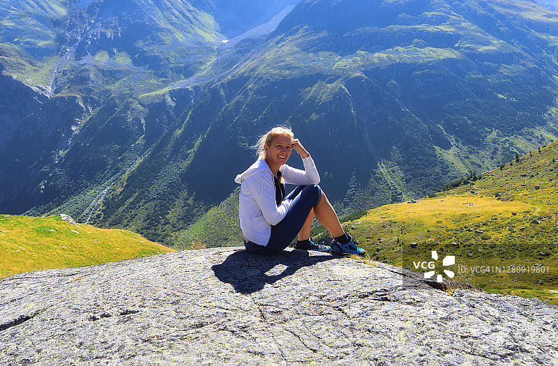 微笑的徒步旅行者坐在瑞士山上的岩石上图片素材