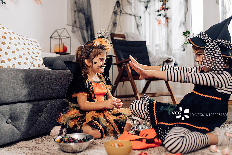 两个可爱的姐妹在万圣节的服装分享糖果和玩耍图片素材