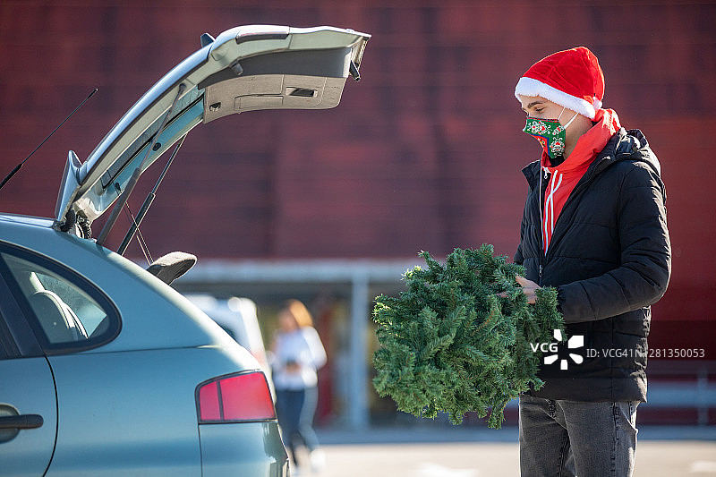 年轻人把刚买的圣诞树放在汽车后备箱里图片素材