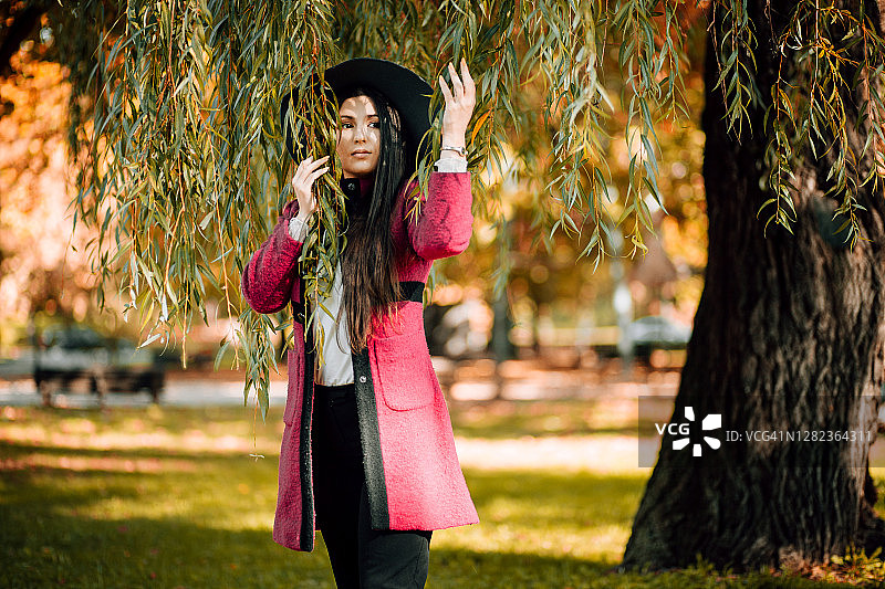 一个穿着大衣的漂亮女孩的肖像，在秋高气平的日子里的公园里图片素材