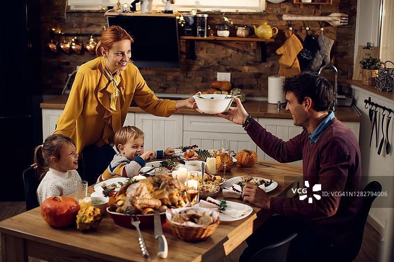 快乐的父母和孩子在餐厅享受感恩节晚餐。图片素材