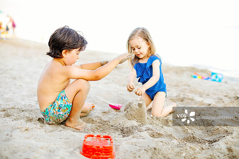 快乐的笑着蹒跚学步的男孩和女孩在沙滩上玩耍图片素材