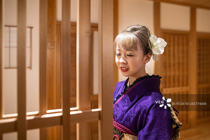 穿着Furisode和服的年轻女子走在日本旅馆的走廊上图片素材