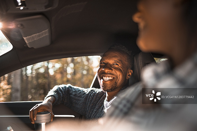 在公路旅行中，微笑的男人在车里看着女性朋友图片素材