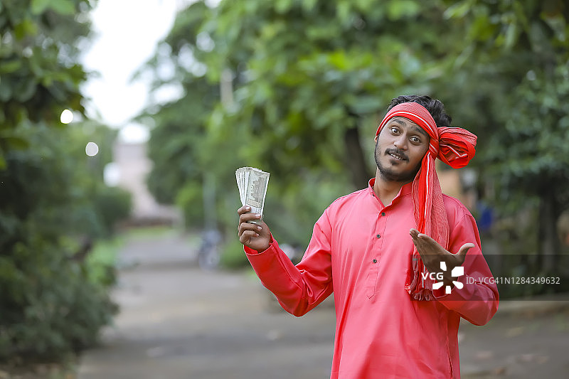 年轻的印度农民拿着钱摆姿势图片素材