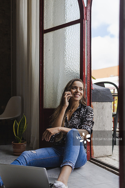 微笑有创意的女商人坐在办公室门口打电话图片素材