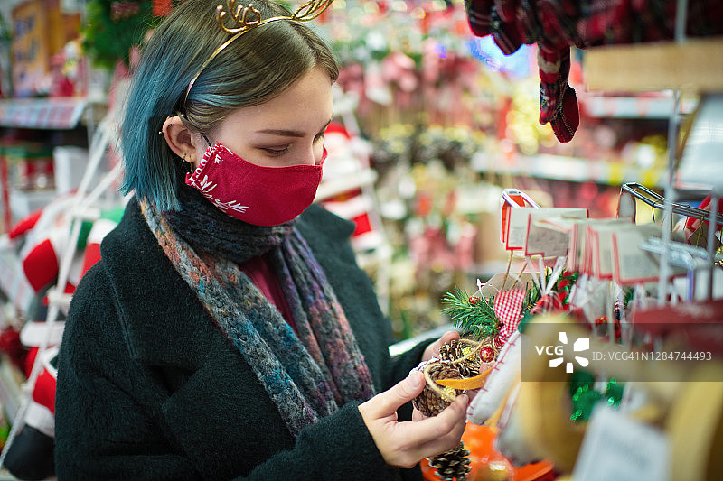 2019冠状病毒病期间，年轻女性戴着防护口罩在圣诞购物图片素材
