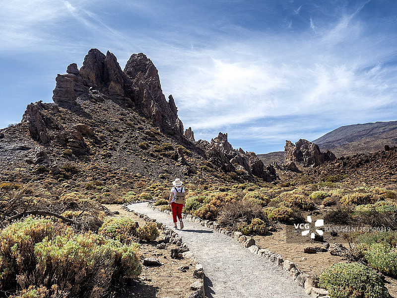 在加那利群岛的特内里费，一名徒步旅行的妇女走过火山景观。图片素材