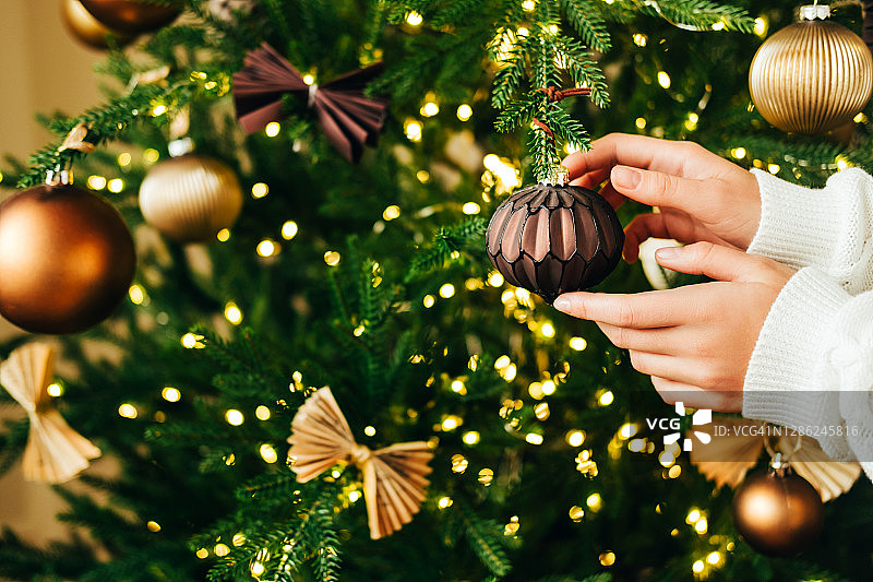 女人的手用复古的圣诞装饰物装饰新年的冷杉树。图片素材