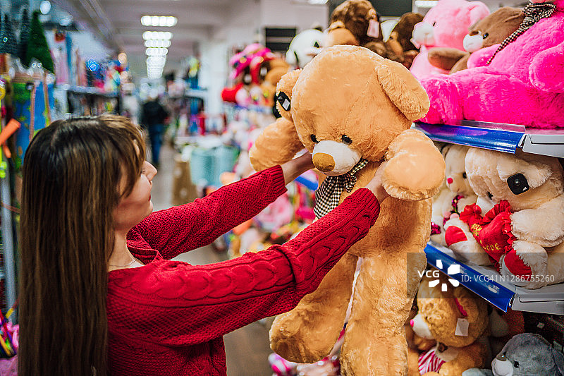 在玩具店挑选玩具熊的女人图片素材