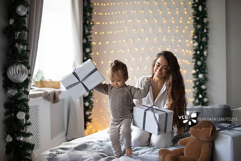 圣诞节的早晨，母亲和女儿在床上打开包装礼物。图片素材