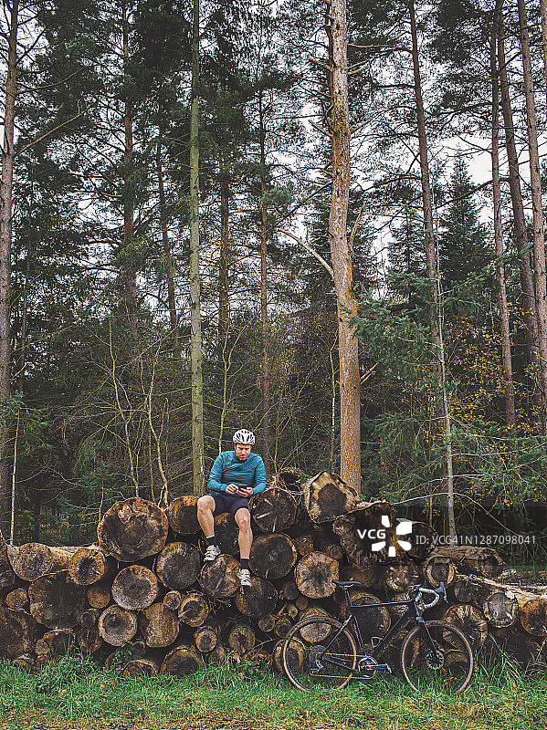骑自行车的人在森林里的一堆木头上休息图片素材