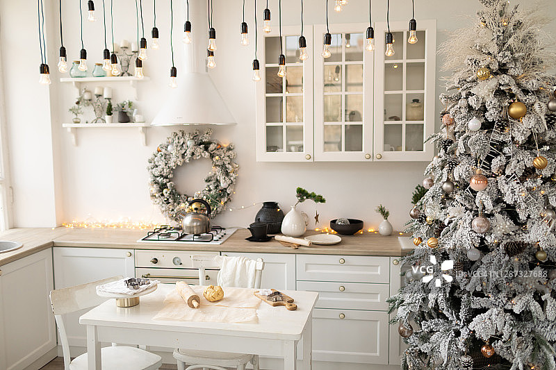 内部白色厨房与圣诞装饰和装饰冷杉树。图片素材