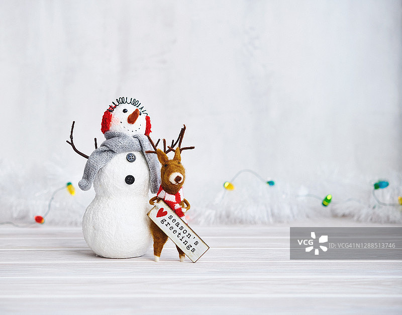 可爱的圣诞背景与雪人和驯鹿持有季节问候标志图片素材