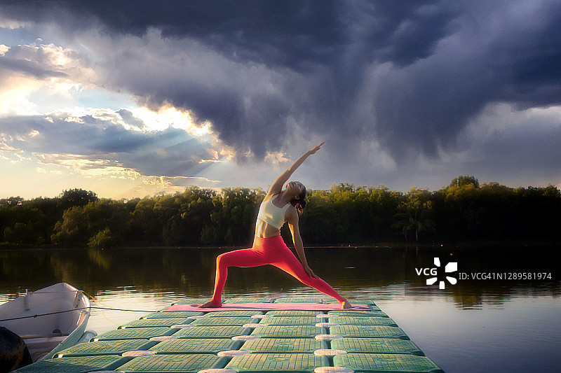 一个年轻女人在码头上练瑜伽。图片素材