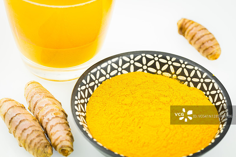 姜黄。一种健康的黄色香料，在世界上许多菜系中使用。各种各样的变种，粉末，在一杯饮用水和作为根图片素材